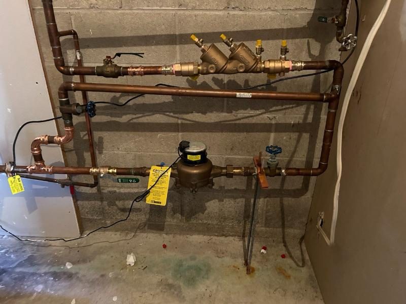 A completed backflow preventer installation with copper piping, meter, and device tags
