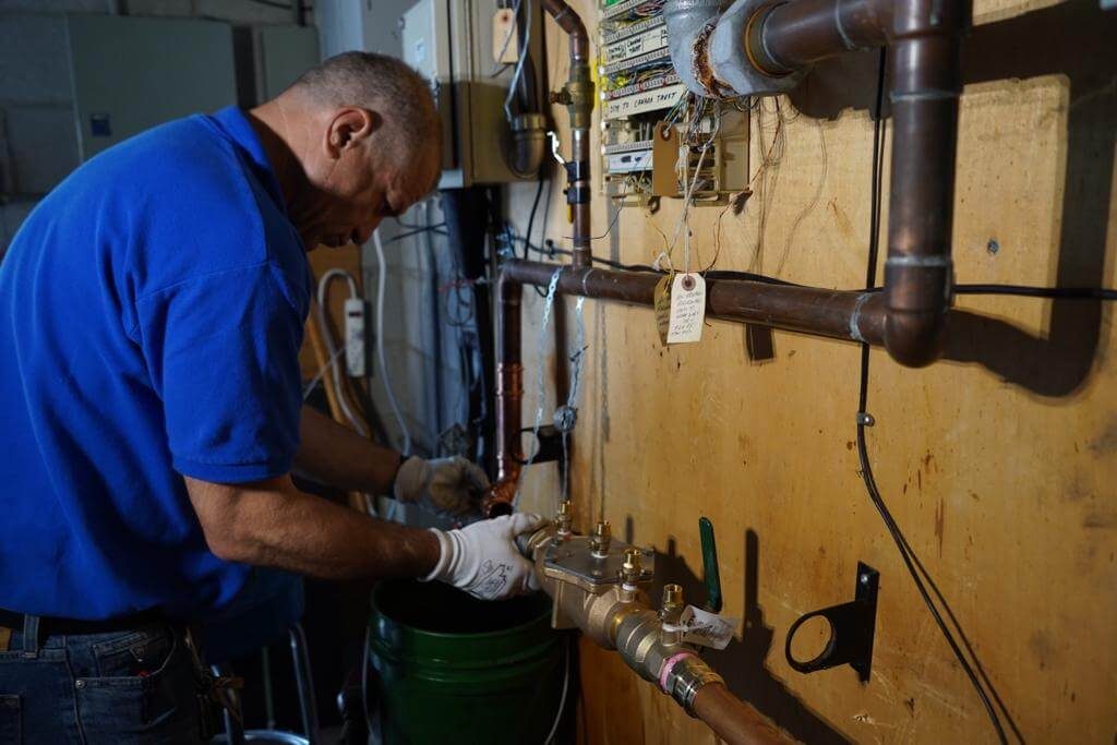 A certified technician inspecting backflow piping during a survey